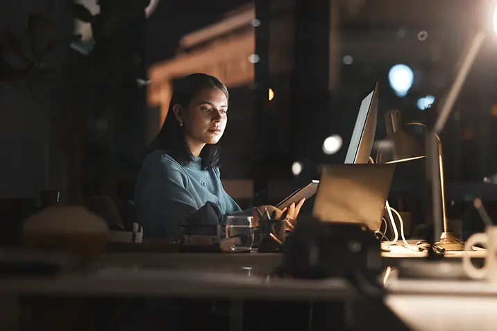 Person arbeitet abends an einem Computerarbeitsplatz