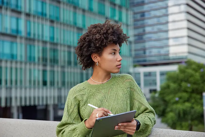 Person arbeitet mit einem Tablet in einem modernen Außenbereich