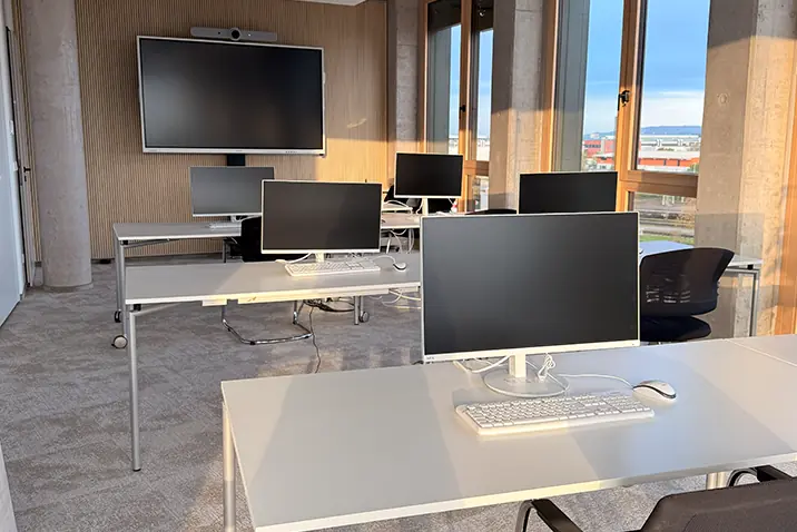 Moderner Schulungsraum mit mehreren Arbeitsplätzen und großen Monitoren