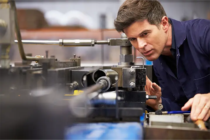 Person prüft eine industrielle Maschine während des Produktionsprozesses