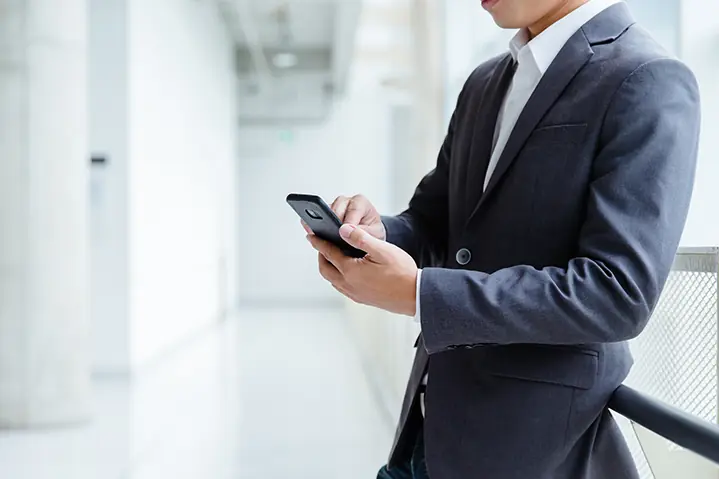 Person nutzt ein Smartphone in einem modernen Büroflur