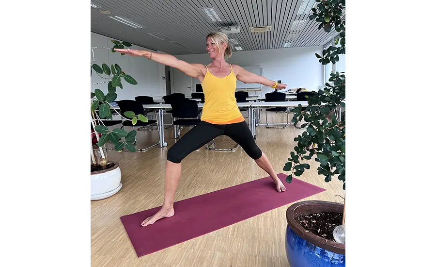 Person führt eine Yoga-Übung auf einer Matte in einem Seminarraum aus