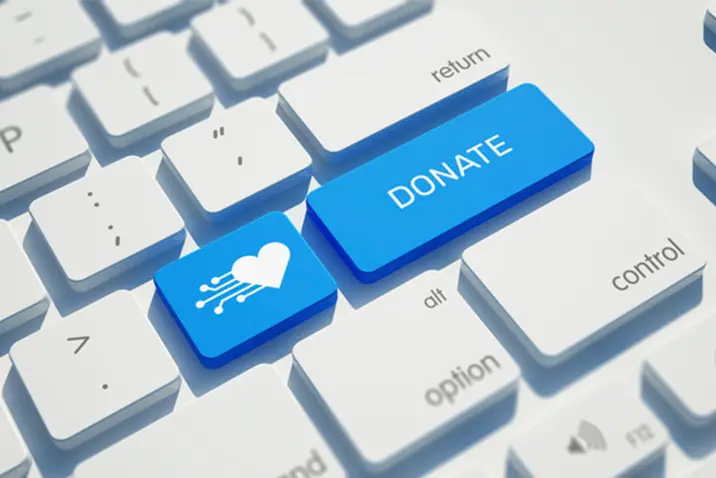 Blaue Taste mit Aufschrift „DONATE“ und Herz‑Symbol auf einer Computertastatur