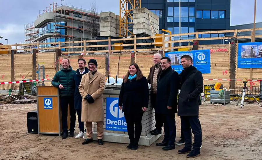 Personengruppe steht an einem Grundstein auf der Baustelle
