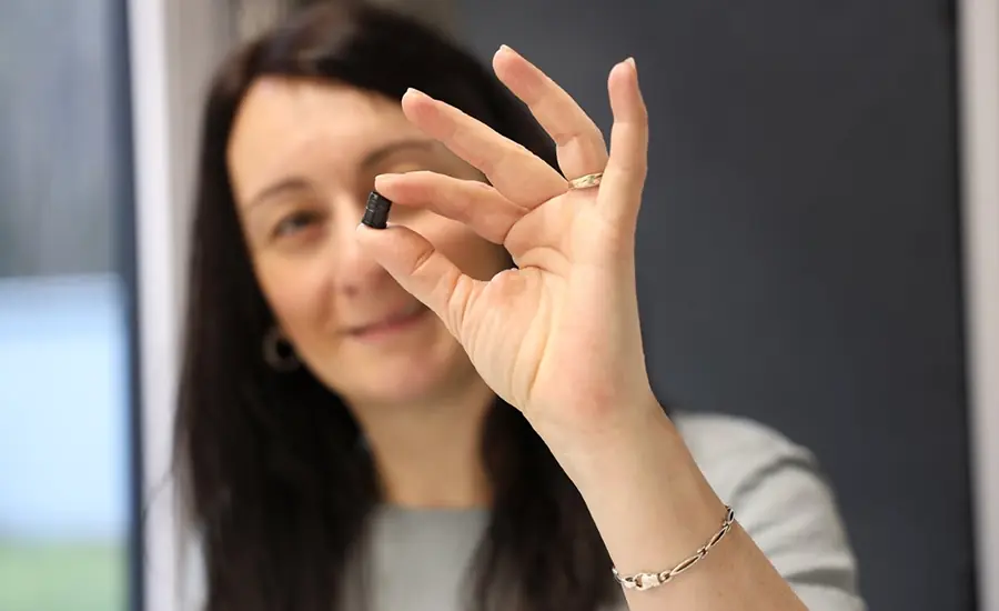 Detailaufnahme eines kleinen technischen Kunststoffbauteils in einer Hand