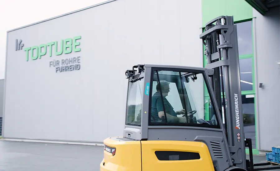Gabelstapler vor Industriegebäude mit Toptube-Logo beim Materialtransport