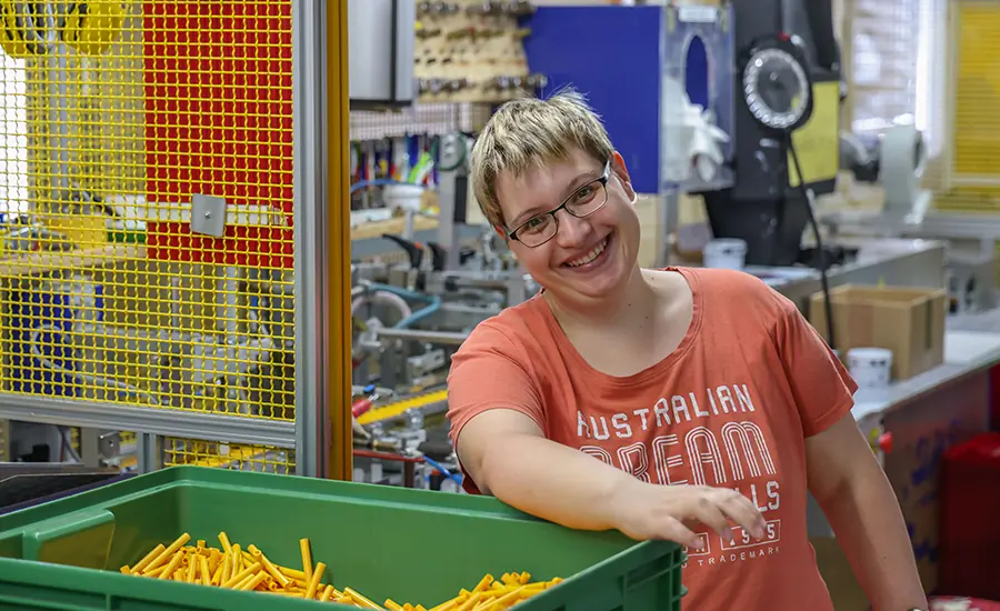 Person arbeitet an einer Produktionsmaschine mit Kunststoffteilen