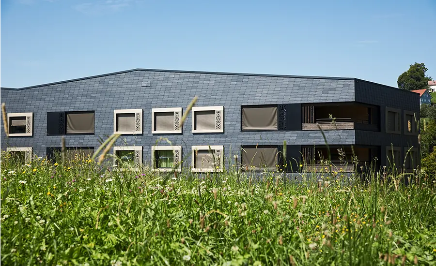 Modernes Gebäude mit dunkler Fassadenverkleidung in naturnaher Umgebung